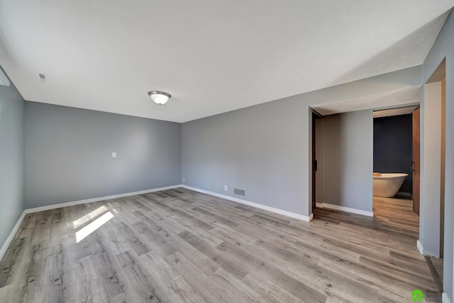 spare room with baseboards and wood finished floors