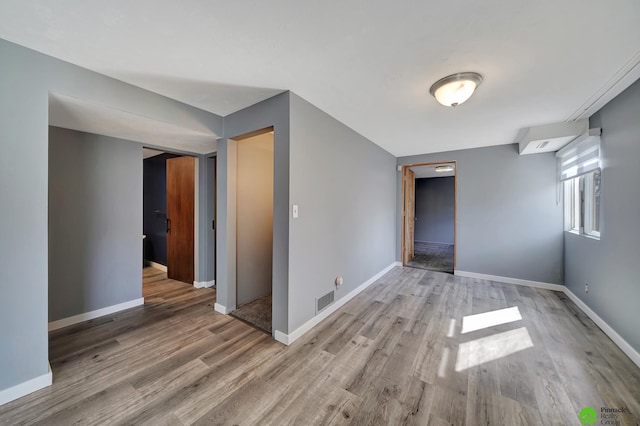 spare room featuring visible vents, baseboards, and wood finished floors