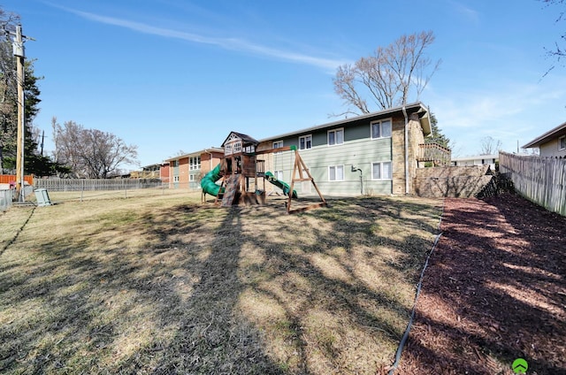 rear view of house featuring a yard, a playground, and a fenced backyard