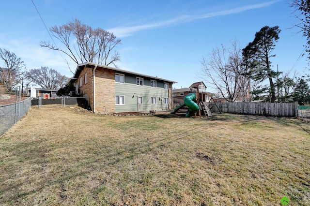 back of house with a playground, a yard, a fenced backyard, and stone siding