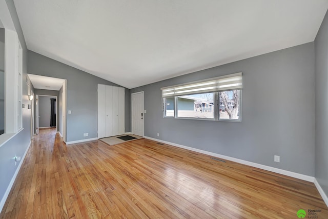 interior space with visible vents, light wood-style flooring, baseboards, and vaulted ceiling