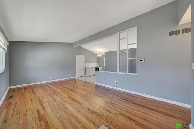 unfurnished room with baseboards, visible vents, vaulted ceiling with beams, light wood-style floors, and a notable chandelier