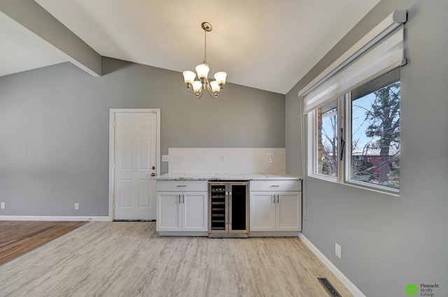 bar featuring vaulted ceiling with beams, baseboards, wine cooler, a chandelier, and light wood-style flooring