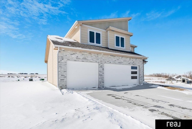 view of front facade with a garage, stone siding, and driveway