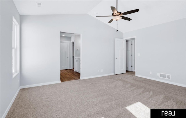 unfurnished bedroom with lofted ceiling, light carpet, visible vents, baseboards, and ensuite bath