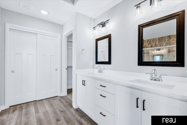 full bath featuring double vanity, visible vents, a sink, and wood finished floors