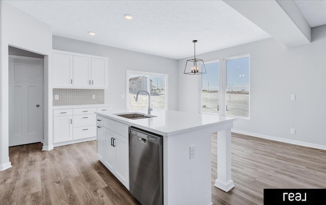 kitchen with white cabinets, dishwasher, a kitchen island with sink, light countertops, and a sink