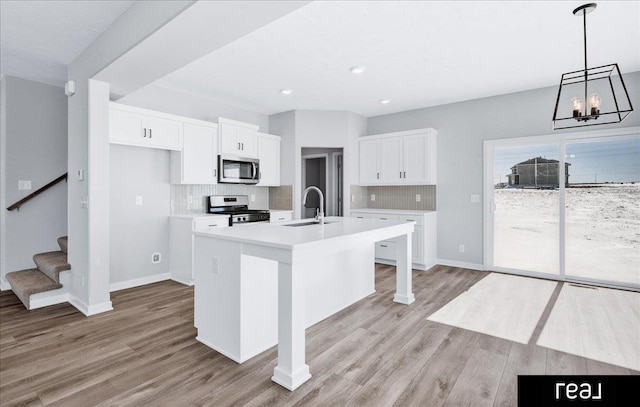 kitchen featuring an island with sink, appliances with stainless steel finishes, light countertops, and white cabinets