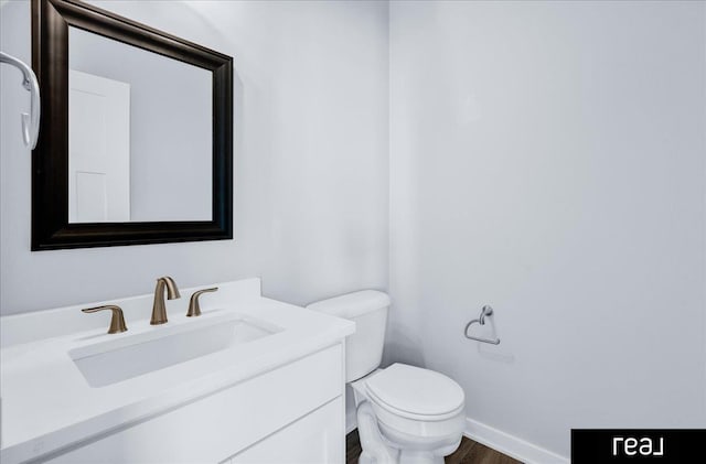 bathroom with wood finished floors, vanity, toilet, and baseboards