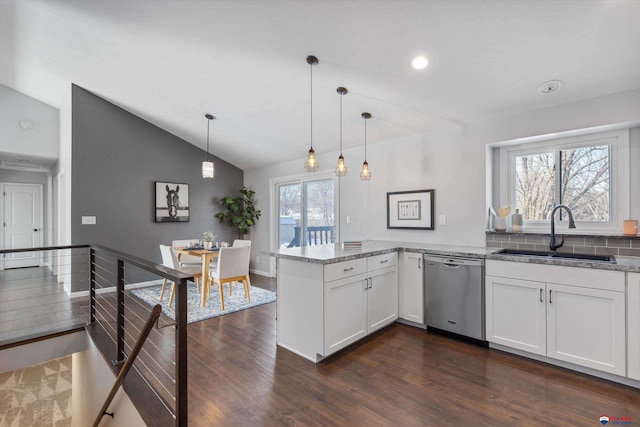 kitchen with a peninsula, a sink, white cabinetry, hanging light fixtures, and stainless steel dishwasher