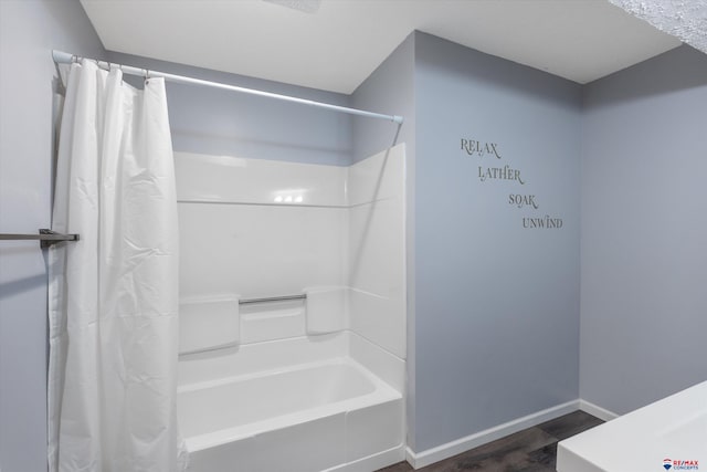 bathroom featuring shower / bath combo and baseboards