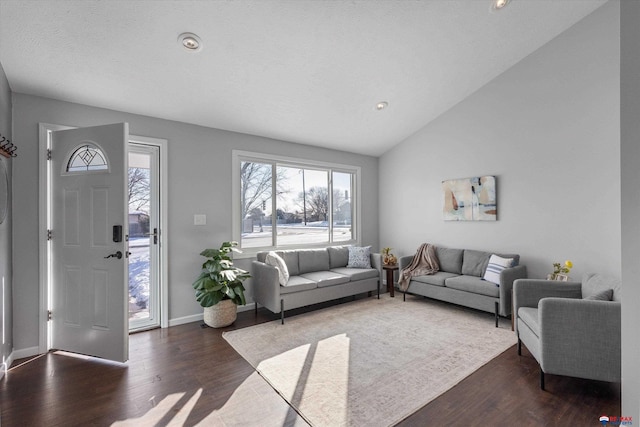 living area featuring vaulted ceiling, dark wood-type flooring, and baseboards