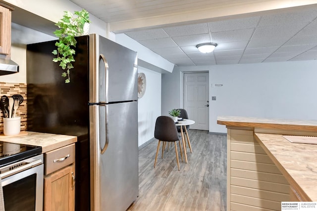 kitchen featuring light wood-style floors, a paneled ceiling, light countertops, and decorative backsplash