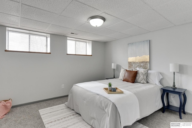 bedroom featuring baseboards, a paneled ceiling, and light colored carpet