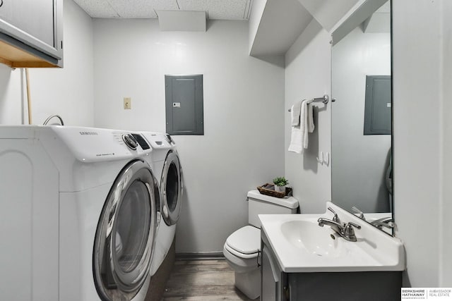 half bathroom with electric panel, toilet, wood finished floors, independent washer and dryer, and vanity