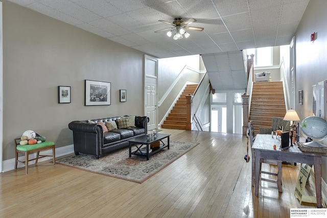 living room featuring ceiling fan, stairway, and light wood finished floors