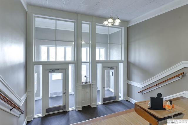 entrance foyer featuring an inviting chandelier, a high ceiling, ornamental molding, and dark wood-type flooring