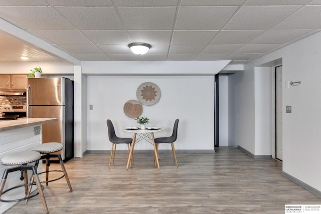 dining space featuring light wood-type flooring, visible vents, a paneled ceiling, and baseboards