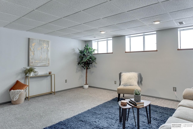 living area featuring baseboards, visible vents, a drop ceiling, and a wealth of natural light