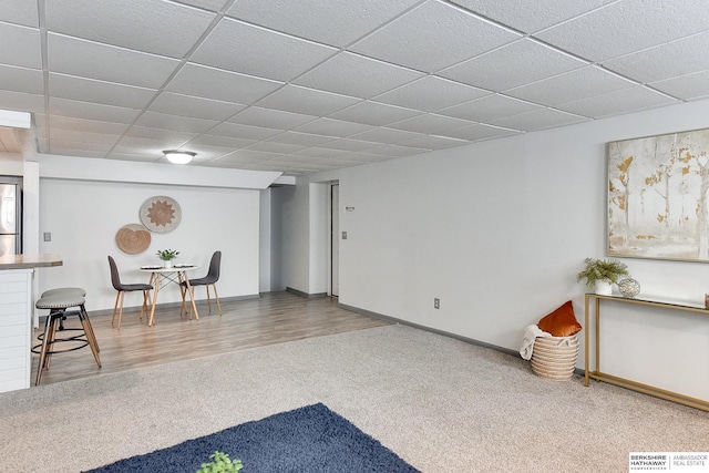 living area featuring baseboards, visible vents, a drop ceiling, and wood finished floors