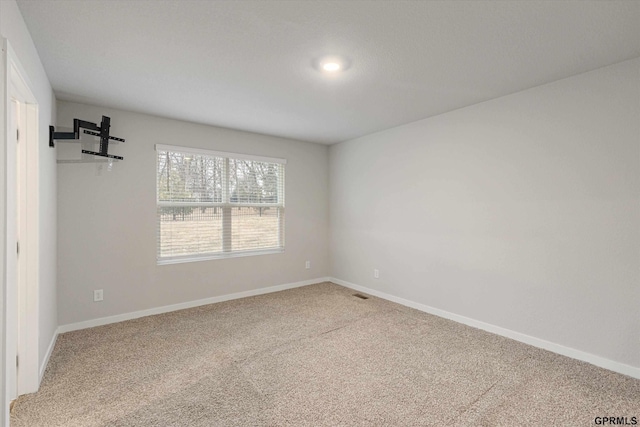 carpeted spare room with visible vents and baseboards