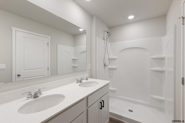 full bathroom featuring recessed lighting, a sink, a shower stall, and double vanity