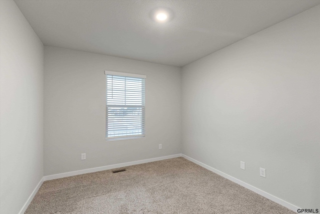 empty room featuring carpet, visible vents, and baseboards