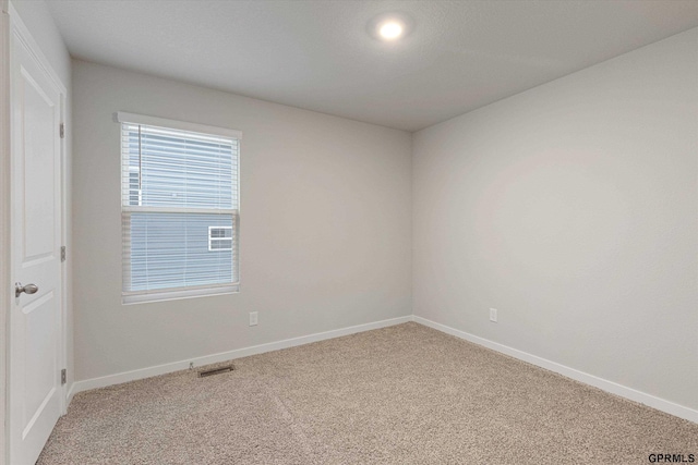 empty room with baseboards, visible vents, and carpet flooring