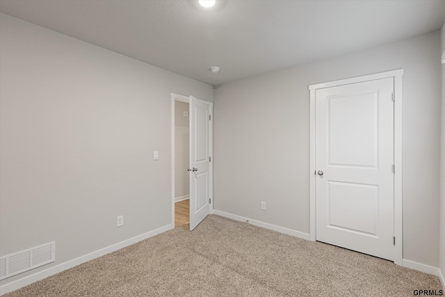 unfurnished bedroom with light colored carpet, visible vents, and baseboards