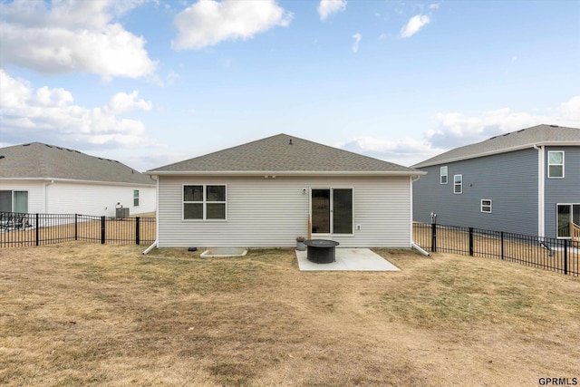 back of house with a fenced backyard, roof with shingles, a patio, and a yard