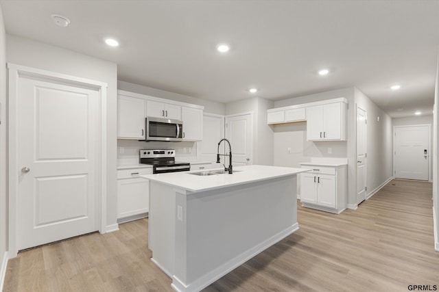 kitchen featuring a sink, white cabinetry, light countertops, appliances with stainless steel finishes, and a center island with sink