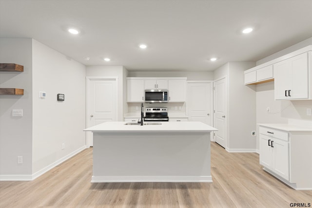 kitchen featuring light countertops, white cabinetry, a center island with sink, and stainless steel appliances