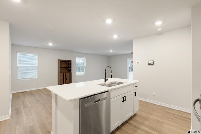 kitchen with a center island with sink, light countertops, stainless steel dishwasher, white cabinetry, and a sink