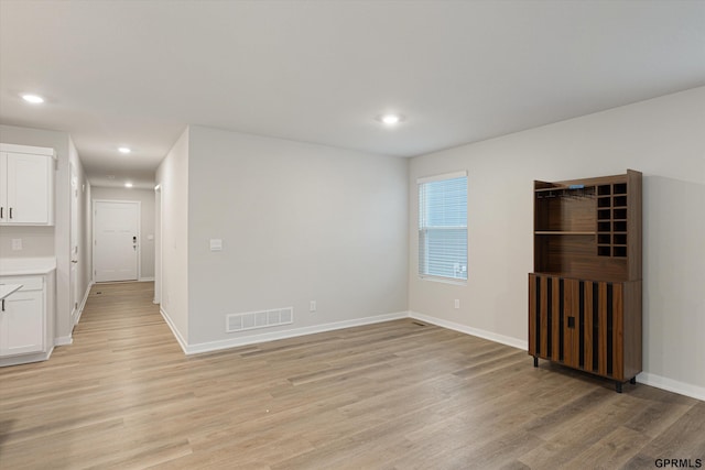 empty room with light wood-type flooring, visible vents, baseboards, and recessed lighting