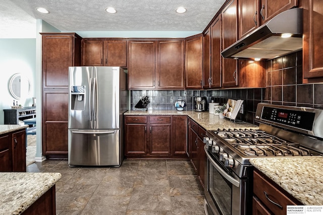 kitchen with stainless steel appliances, decorative backsplash, a textured ceiling, light stone countertops, and under cabinet range hood