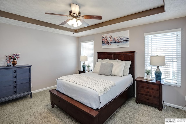 bedroom featuring light carpet, baseboards, a raised ceiling, and a textured ceiling