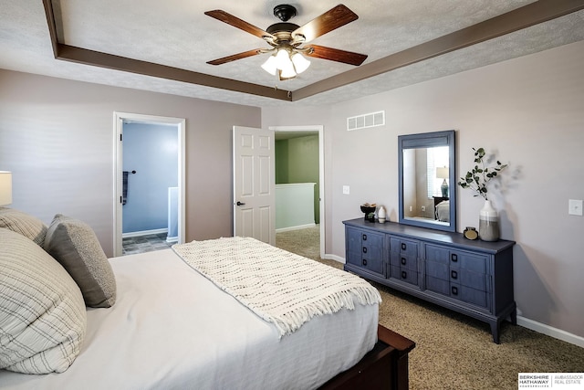 bedroom with a textured ceiling, a raised ceiling, visible vents, and baseboards