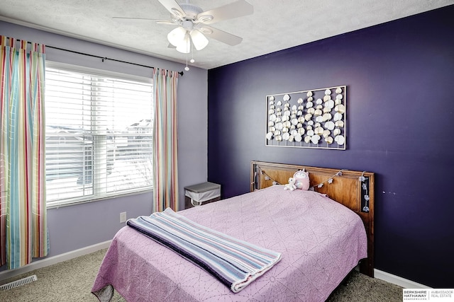 bedroom with a textured ceiling, carpet flooring, visible vents, and baseboards