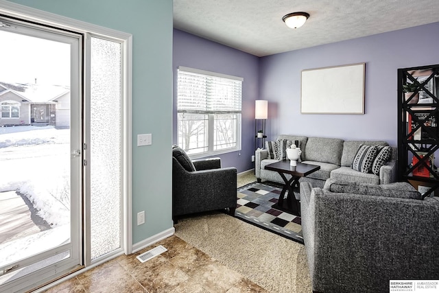 living area featuring visible vents, a textured ceiling, and baseboards