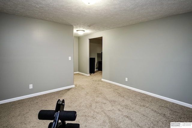 unfurnished room featuring light carpet, a textured ceiling, and baseboards