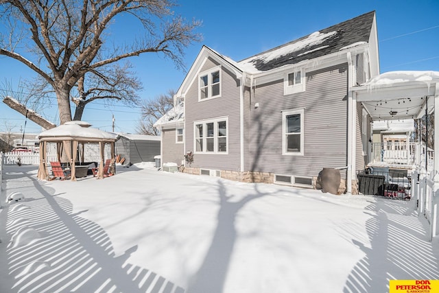 snow covered house featuring fence and a gazebo