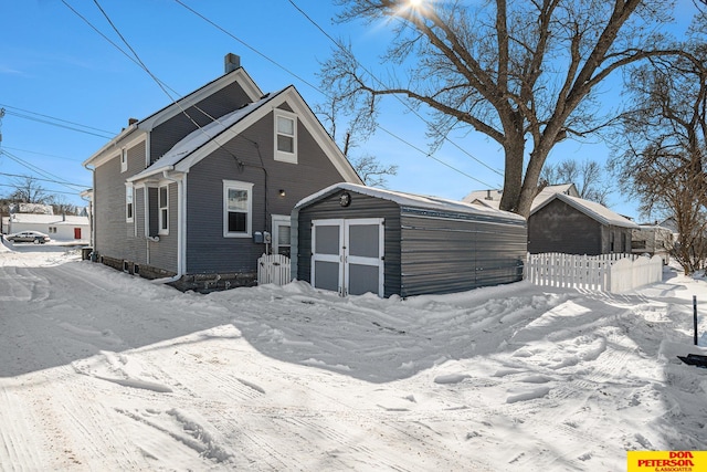 exterior space with a storage unit, a chimney, fence, and an outdoor structure