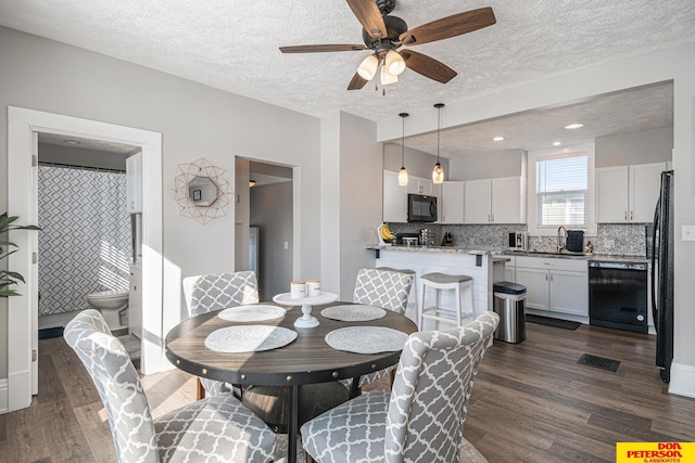 dining room with a ceiling fan, visible vents, dark wood finished floors, and a textured ceiling