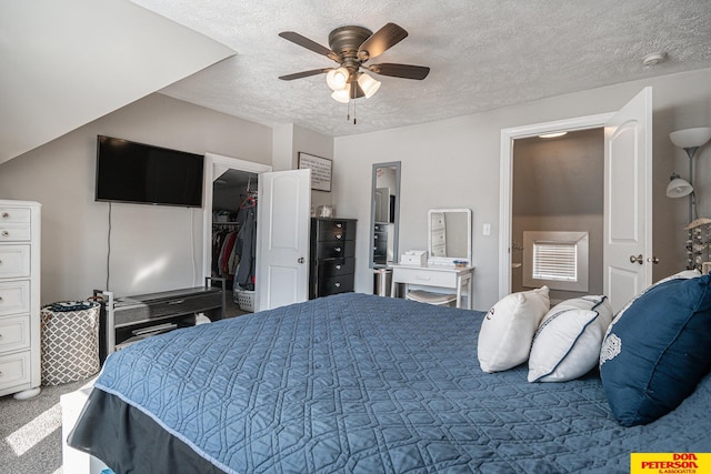 carpeted bedroom with a ceiling fan, a closet, a textured ceiling, and a spacious closet