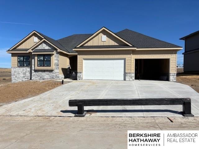 craftsman house featuring stone siding, board and batten siding, an attached garage, and driveway