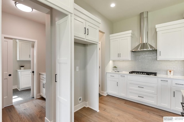 21802 Parkview Dr, Gretna, NE 68028 - kitchen featuring gas cooktop, wall chimney range hood, light wood-style flooring, decorative backsplash, and white cabinetry