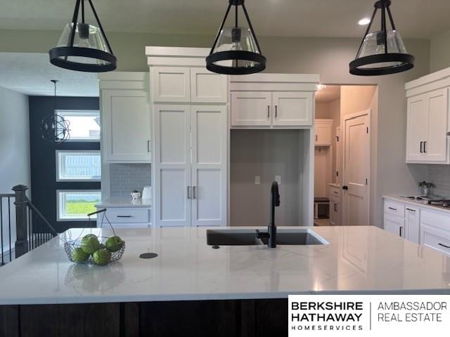 21802 Parkview Dr, Gretna, NE 68028 - kitchen with a large island with sink, white cabinetry, backsplash, and light stone counters