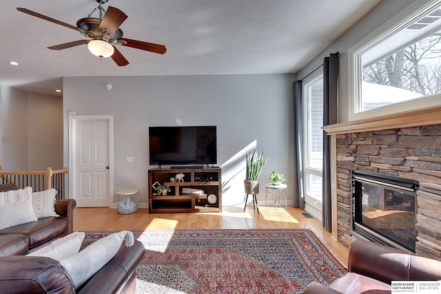 living room featuring a healthy amount of sunlight, light wood-type flooring, a fireplace, and baseboards