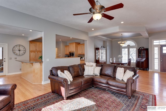 living room featuring ceiling fan with notable chandelier, light wood-type flooring, baseboards, and recessed lighting