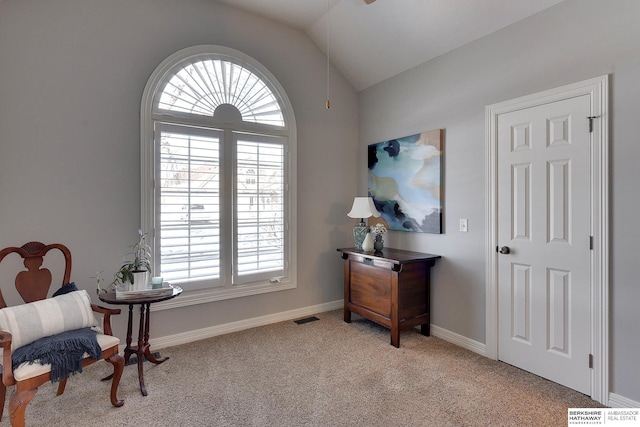 living area with vaulted ceiling, baseboards, visible vents, and light colored carpet